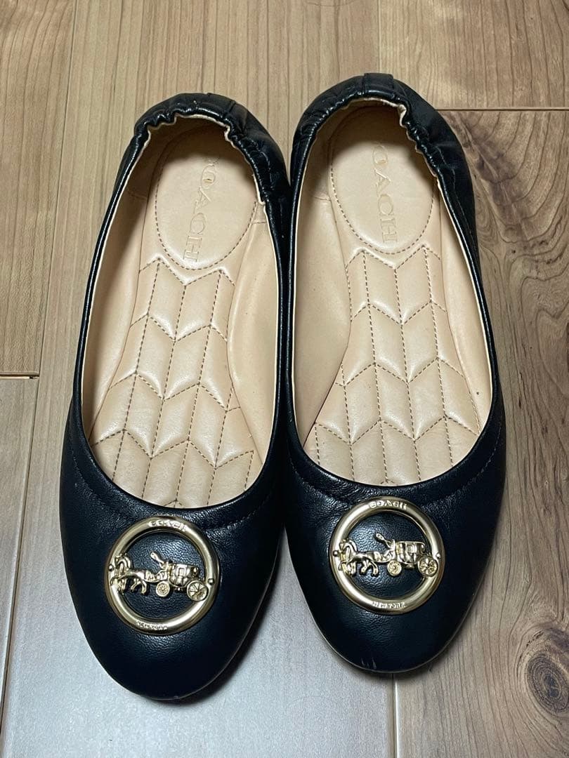 黒のフラットシューズ 金色のバッジ付き
