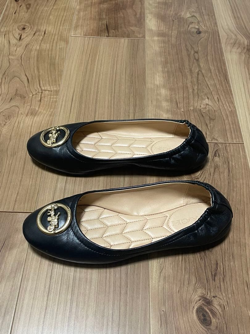 黒のフラットシューズ 金色のバッジ付き