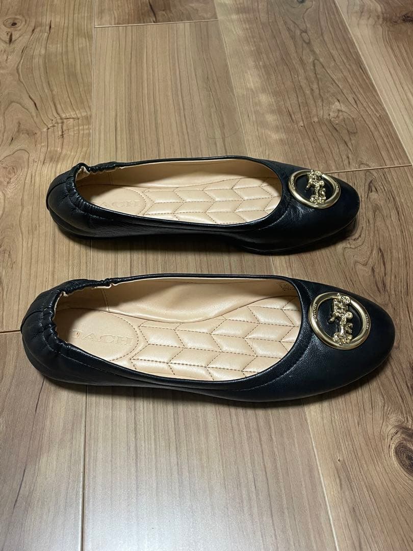 黒のフラットシューズ 金色のバッジ付き
